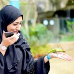 seorang wanita pelancong asing sedang melihat unggas di tangannya semasa lawatan di entopia penang